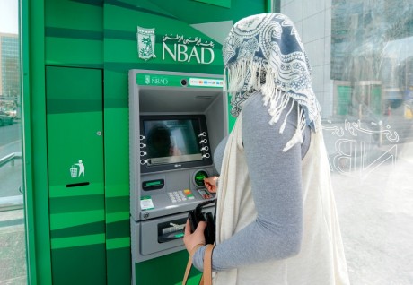 Une femme devant un distributeur de la Banque Nationale d'Abou Dabi, REUTERS/Ben Job