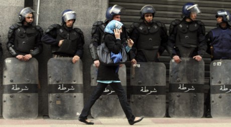 Une femme passe devant des policiers anti-émeutes lors d'une manifestation à Alger, le 12 février 2011. REUTERS/Louafi Larbi
