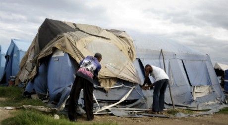 Des hommes tentent de rapiécer leurs tentes à Cité Soleil, Haïti, le 4 août 2011. REUTERS/Swoan Parker