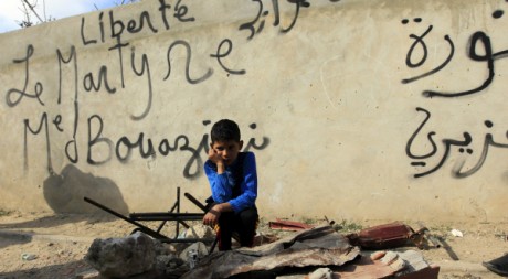Un garçon devant un mur plein de graffitis à Sidi Bouzid, ville de Mohamed Bouazizi, 19 janvier 2011. REUTERS/Zohra Bensemra