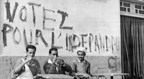 Des Algériens prennent leur café sous une inscription appelant à voter pour l'indépendance à Alger le 17 juin 1962. AFP/FARENC