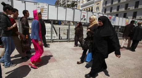 Des femmes marchent devant pancartes électorales à Alger le 19 avril 2012. Reuters/ Zohra Bensemra