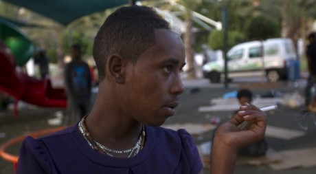 Un migrant africain fume une cigarette devant le parc où il a passé sa nuit, le 26 mai à Tel-Aviv. REUTERS/Ronen Zvulen 