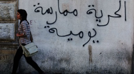 Une jeune fille passe devant une inscription:"la liberté, une pratique quotidienne"Reuters