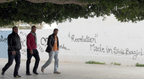 Des Tunisiens devant un mur de graffiti à Sidi Bouzid, décembre 2012. ©KHALIL / AFP