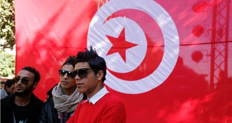 Des jeunes devant un drapeau tunisien pour le deuxième anniversaire  de la révolte à Tunis, 13 janvier 2013 / REUTERS