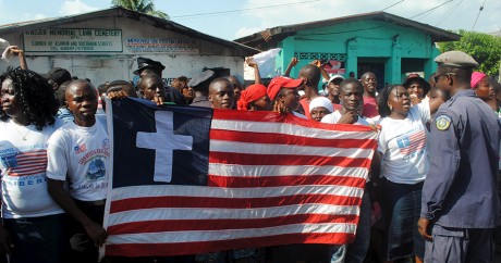 Des habitants du Liberia brandissent un drapeau du pays où une croix a été ajoutée. Crédit photo: REUTERS/James Giahyue